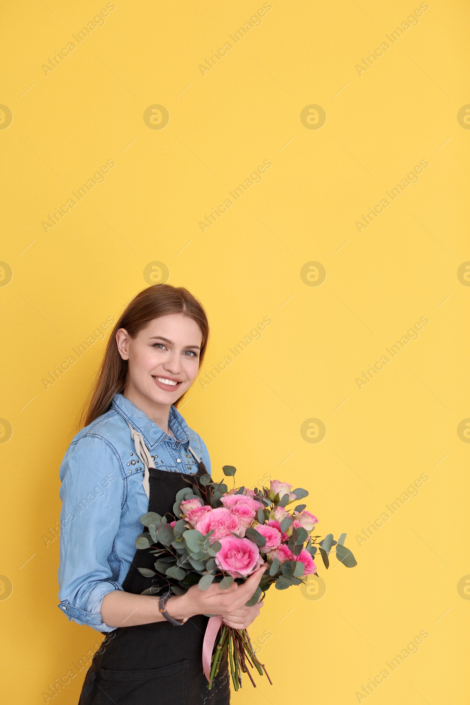 Photo of Female florist holding bouquet of beautiful flowers on color background