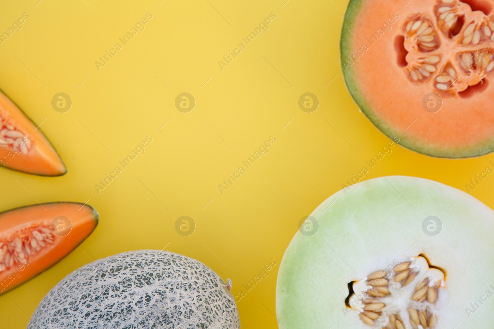 Photo of Different tasty ripe melons on yellow background, flat lay. Space for text