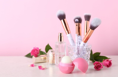 Beautiful composition with lip balm and perfume on white wooden table