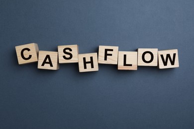 Image of Wooden cubes with phrase Cash FLow on grey background, flat lay
