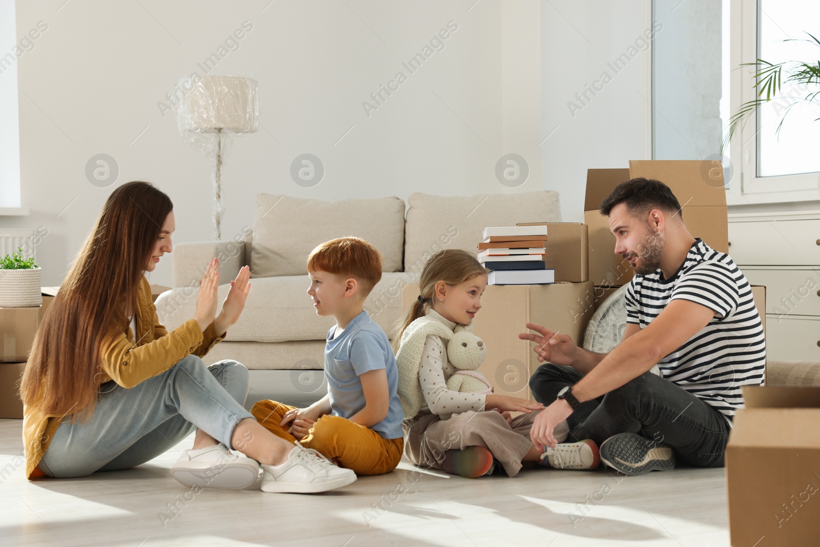 Photo of Happy family playing on floor in new apartment. Moving day