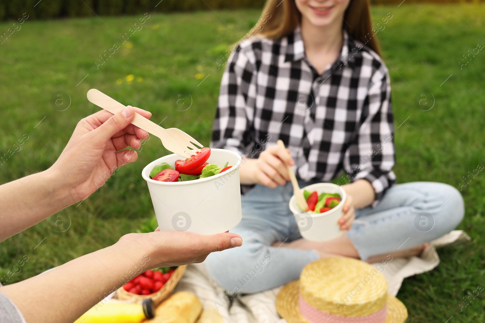 Photo of Friends having picnic on green grass in park, closeup