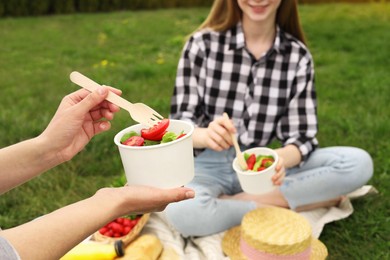 Friends having picnic on green grass in park, closeup