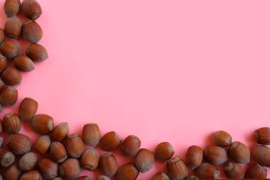 Photo of Many hazelnuts on pink background, flat lay. Space for text