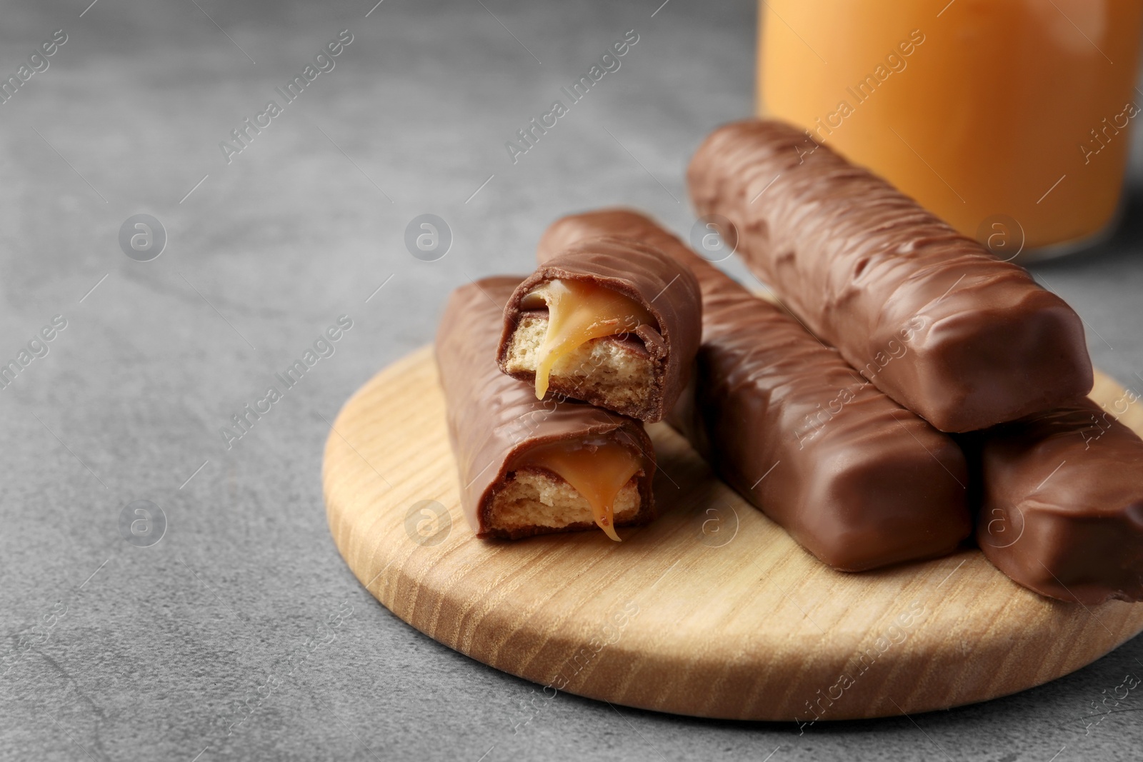 Photo of Sweet tasty chocolate bars with caramel on grey table. Space for text