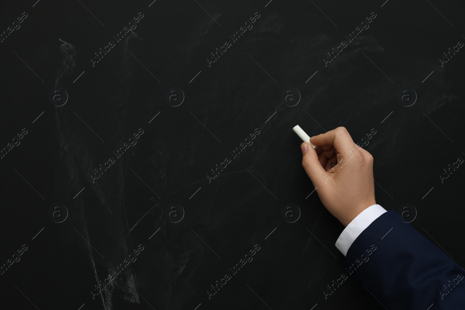 Photo of Man with white chalk near blackboard, closeup. Space for text