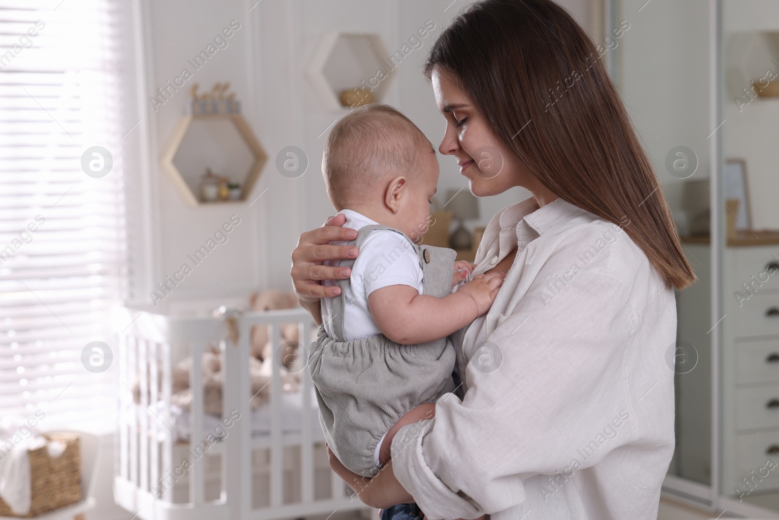 Photo of Happy young mother with her baby in nursery. Space for text