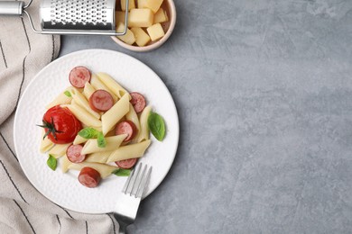 Tasty pasta with smoked sausage, tomato and basil served on grey table, flat lay. Space for text