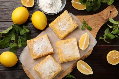 Photo of Tasty lemon bars with powdered sugar and mint on wooden table, flat lay