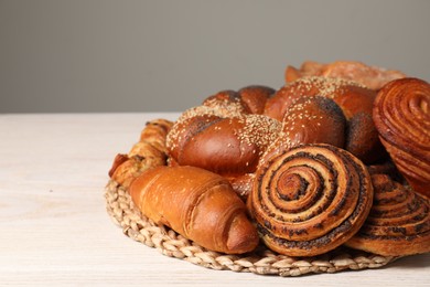 Different tasty freshly baked pastries on white wooden table, space for text