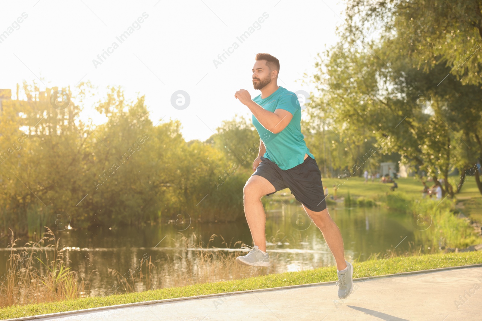 Photo of Young man running near pond in park. Space for text