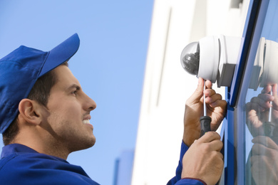 Technician installing CCTV camera on wall outdoors