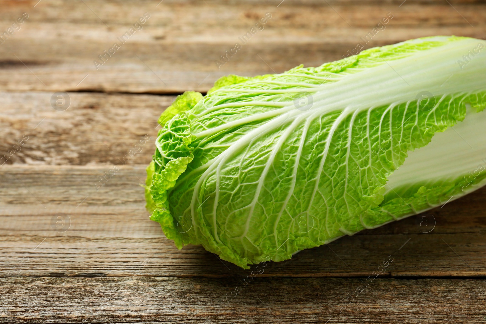 Photo of Fresh ripe Chinese cabbage on wooden table, closeup. Space for text