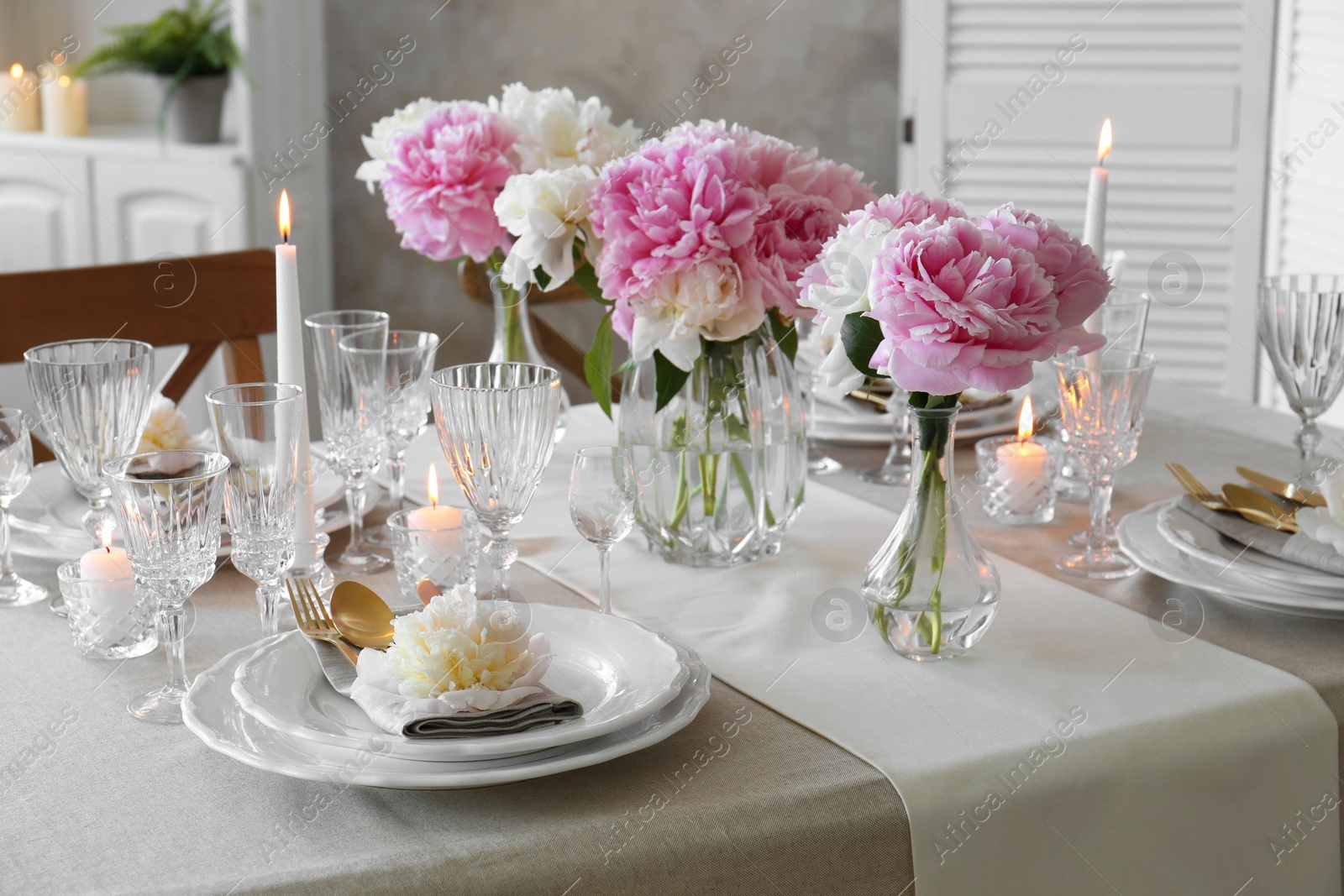 Photo of Stylish table setting with beautiful peonies and burning candles indoors