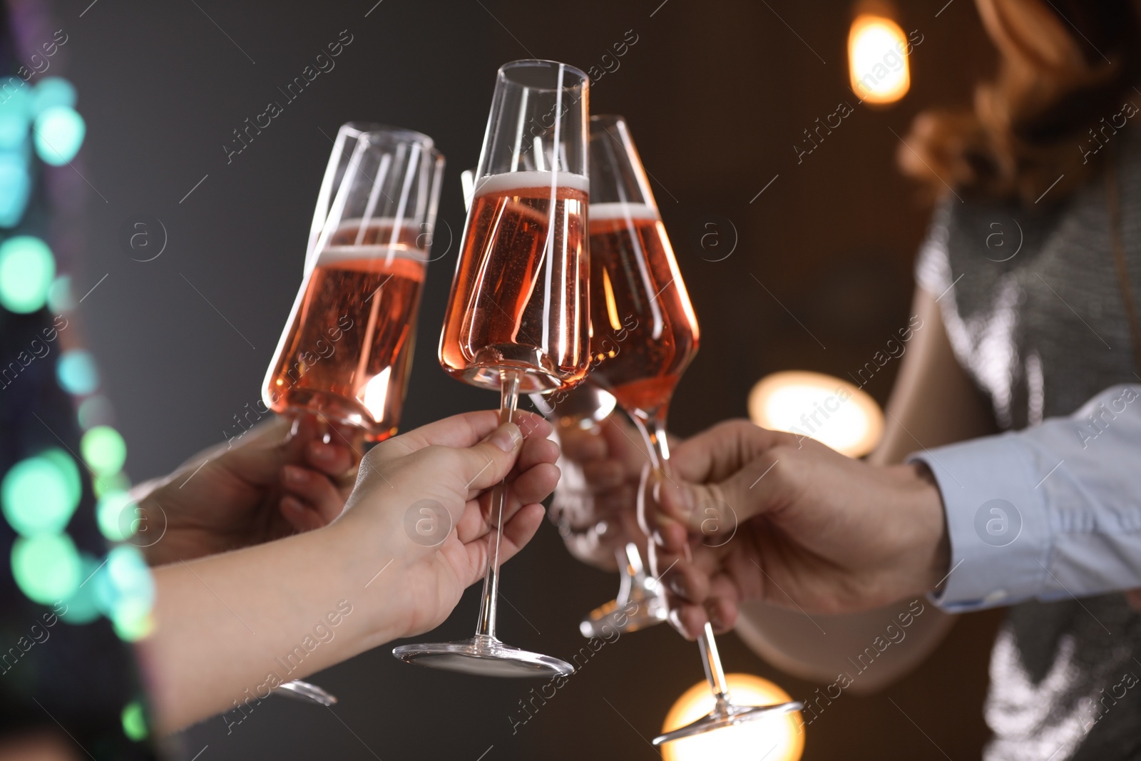 Photo of Friends clinking glasses with champagne on blurred background, closeup