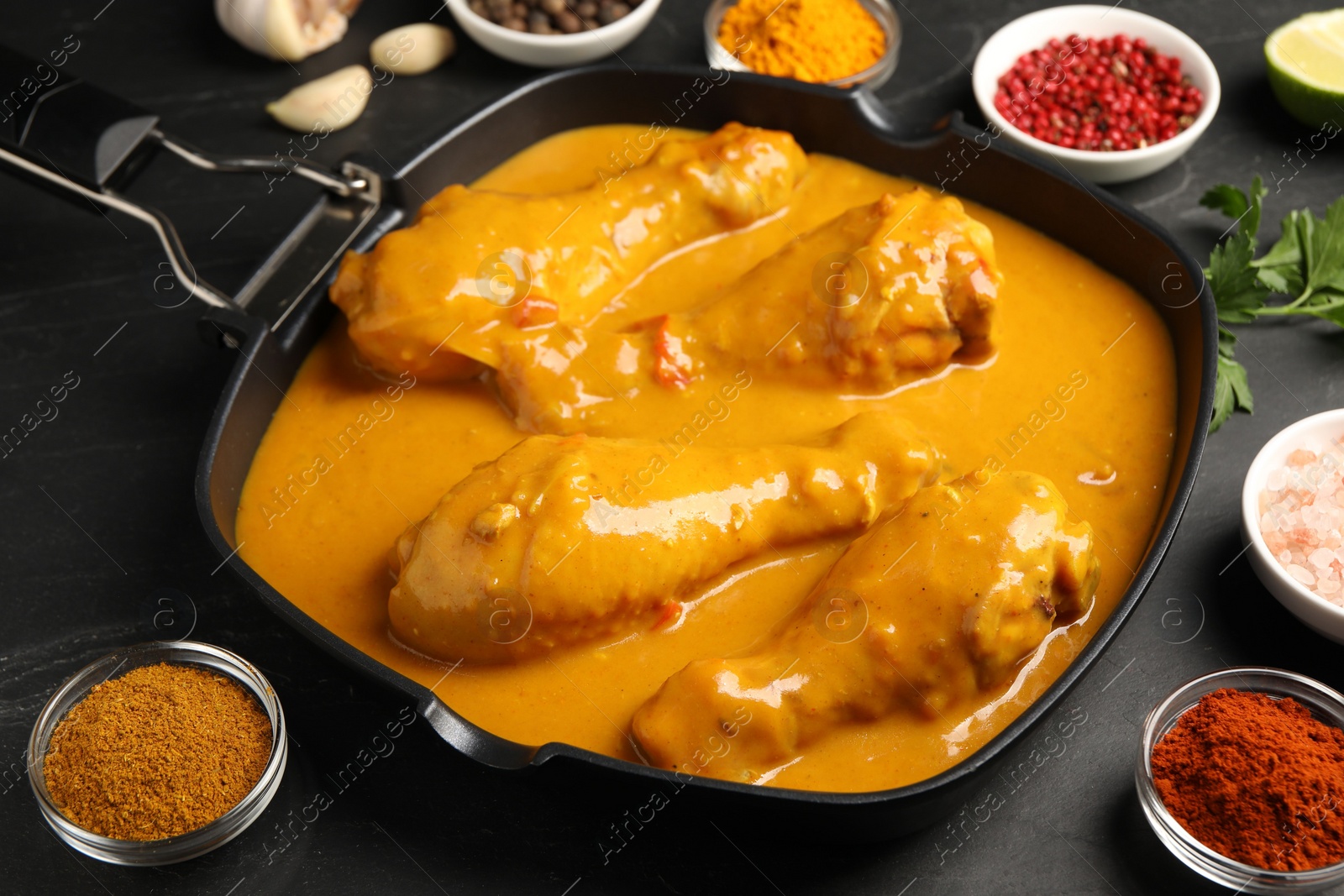 Photo of Tasty chicken curry and ingredients on black table