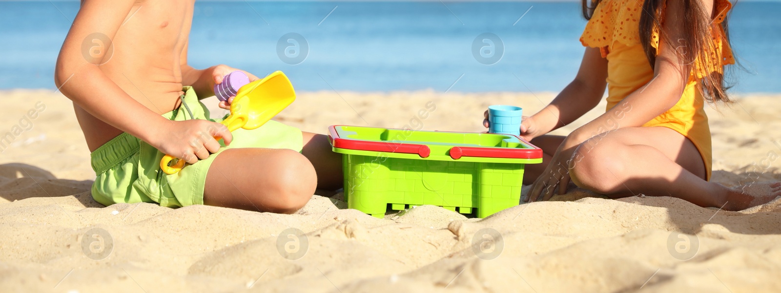 Image of Cute little children playing with plastic toys on sandy beach, closeup. Banner design