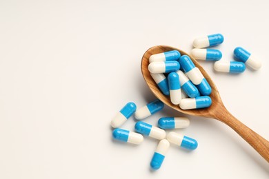 Photo of Antibiotic pills and spoon on white background, top view. Space for text