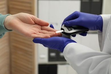 Diabetes. Doctor checking patient's blood sugar level with glucometer in clinic, closeup