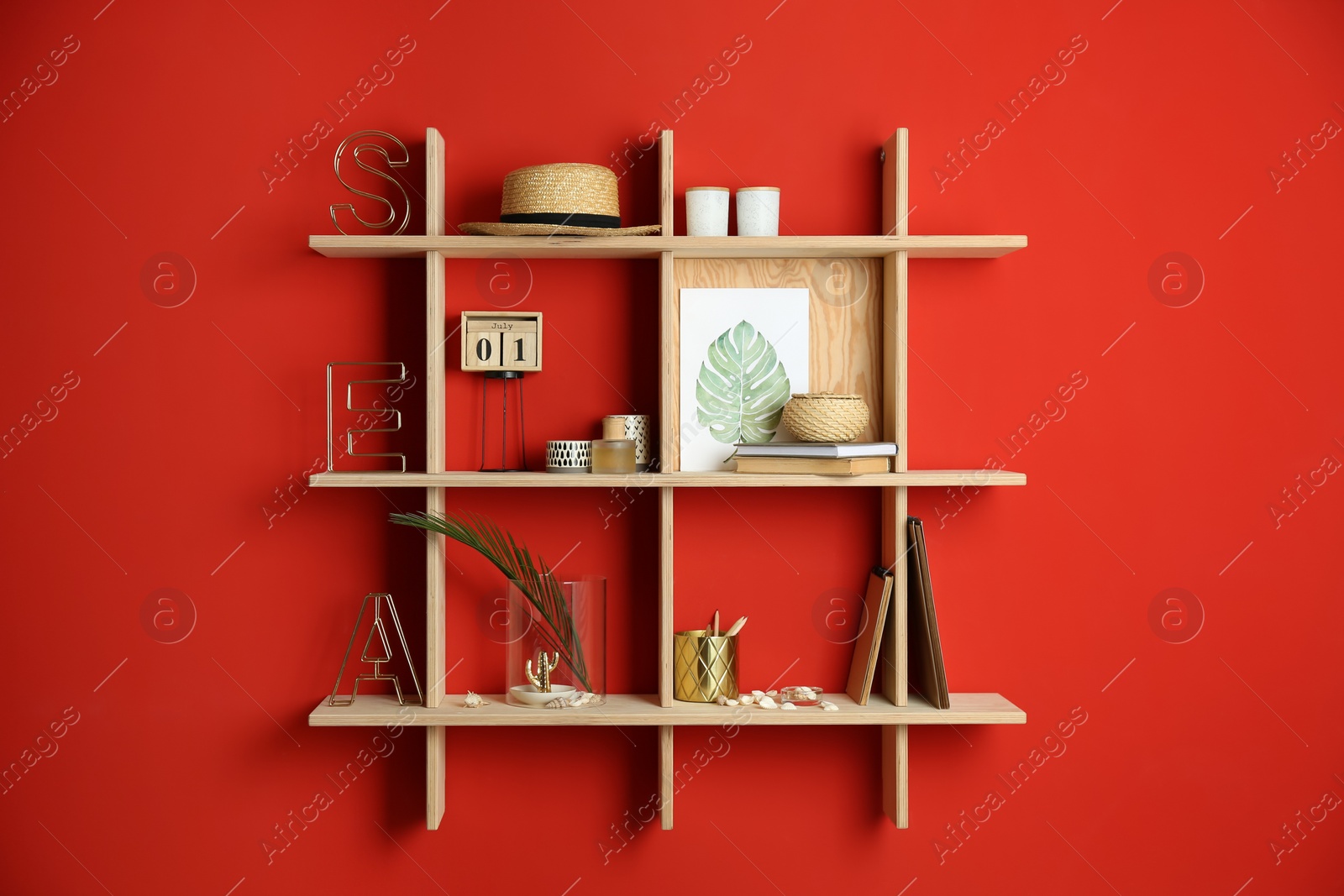 Photo of Stylish wooden shelves with decorative elements on red wall