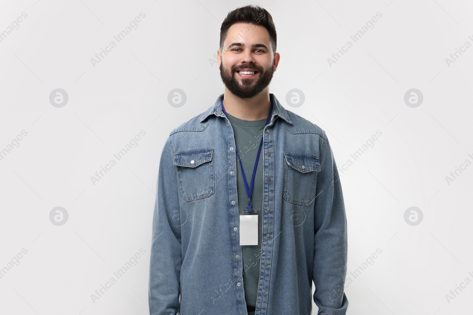 Photo of Happy young man with blank badge on grey background