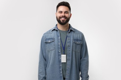 Happy young man with blank badge on grey background