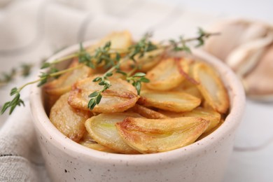 Photo of Fried garlic cloves and thyme in bowl on table, closeup