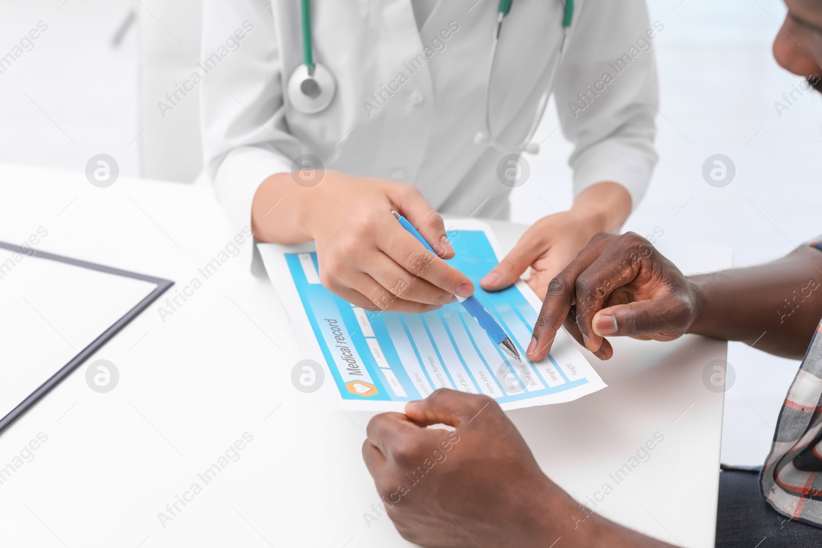 Photo of Young doctor consulting African-American patient in hospital