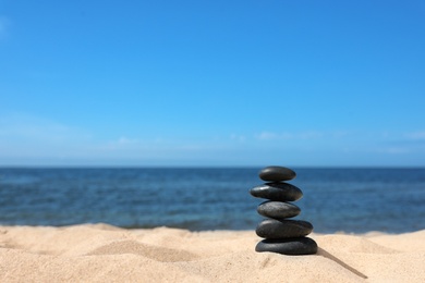 Photo of Stack of stones on sand near sea, space for text. Zen concept