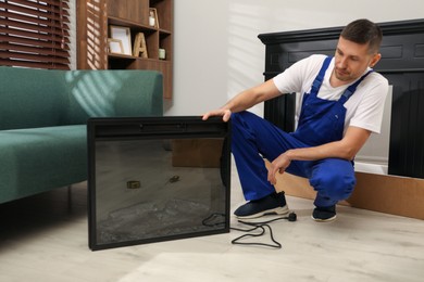 Photo of Professional technician installing electric fireplace in room