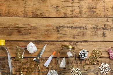 Instruments and materials for snow globe on wooden table, flat lay. Space for text