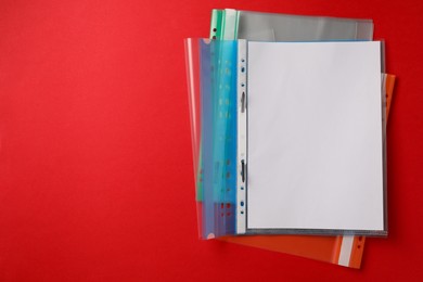 File folders with punched pockets on red background, flat lay. Space for text