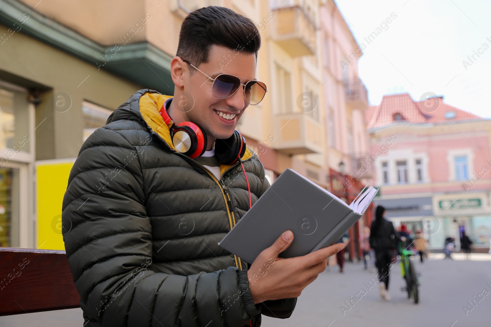 Photo of Handsome man reading book on city street