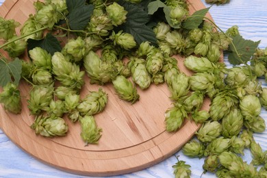 Photo of Board and fresh green hops on pale blue wooden table