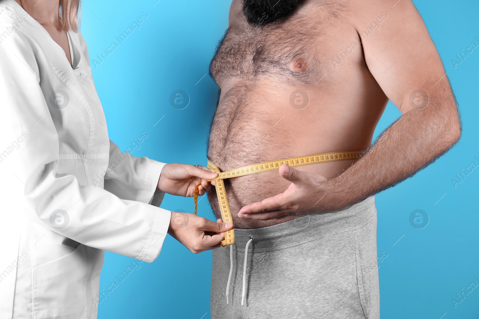 Photo of Doctor measuring fat man's waist on color background. Weight loss