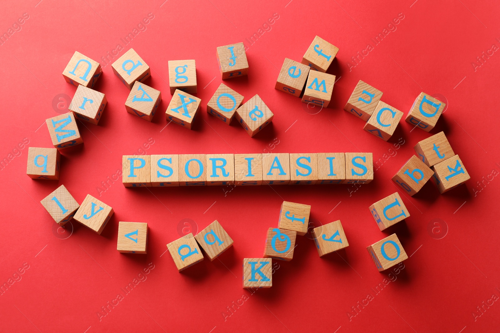 Photo of Word Psoriasis made of wooden cubes with letters on red background, flat lay