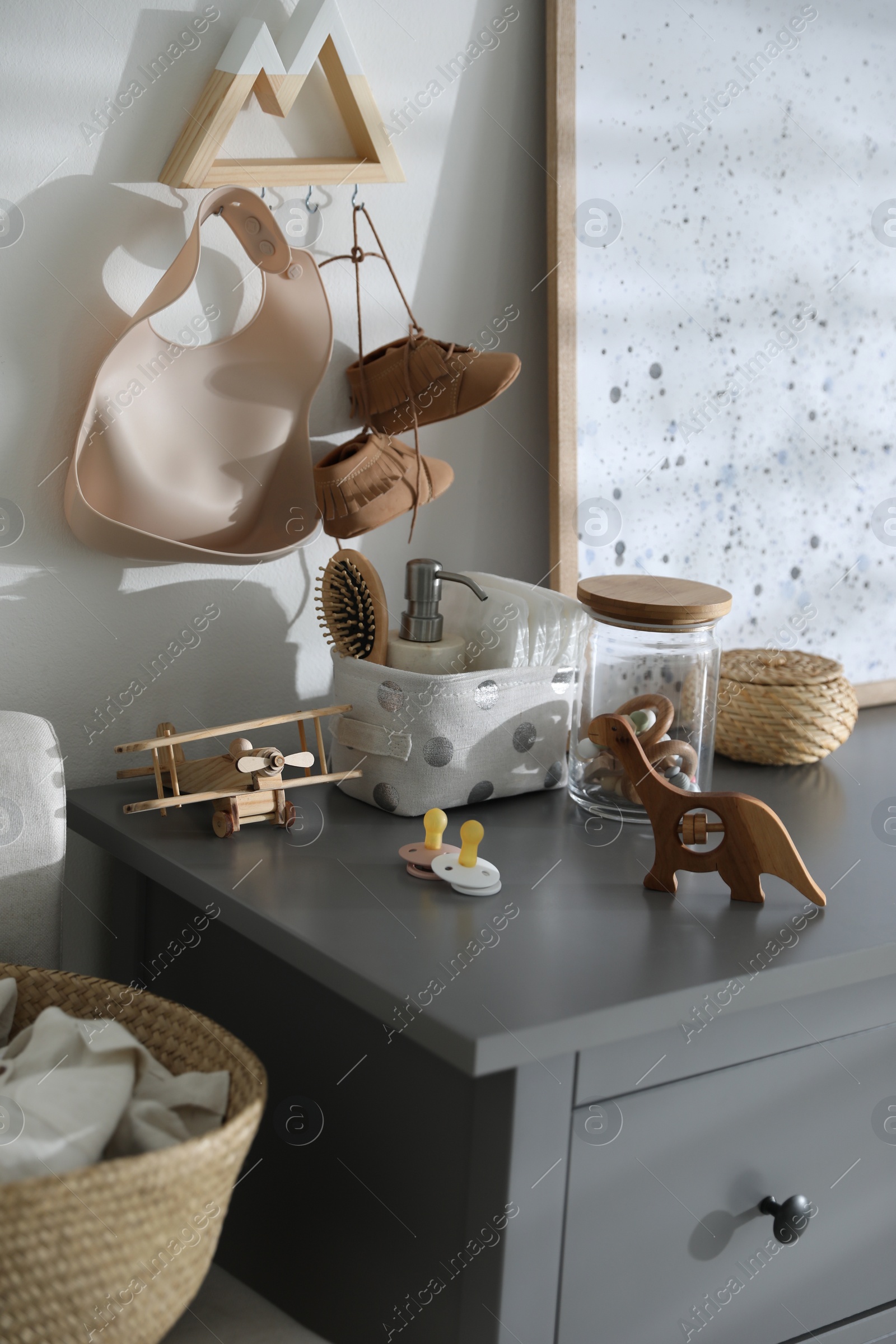 Photo of Wooden toys and different accessories on grey chest of drawers in child room