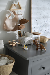 Photo of Wooden toys and different accessories on grey chest of drawers in child room