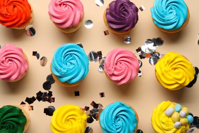 Photo of Delicious cupcakes with bright cream and confetti on beige background, flat lay