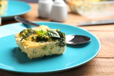 Photo of Tasty broccoli casserole served on wooden table, closeup