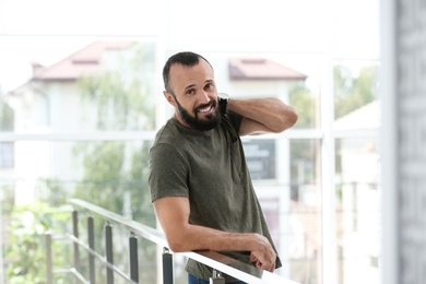 Portrait of handsome mature man leaning on handrail indoors