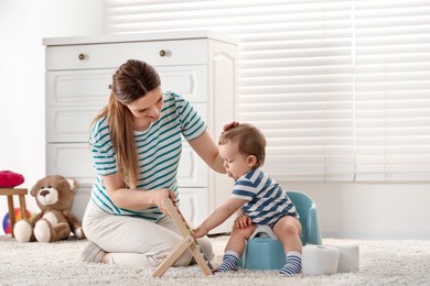 Photo of Mother training her child to sit on baby potty indoors