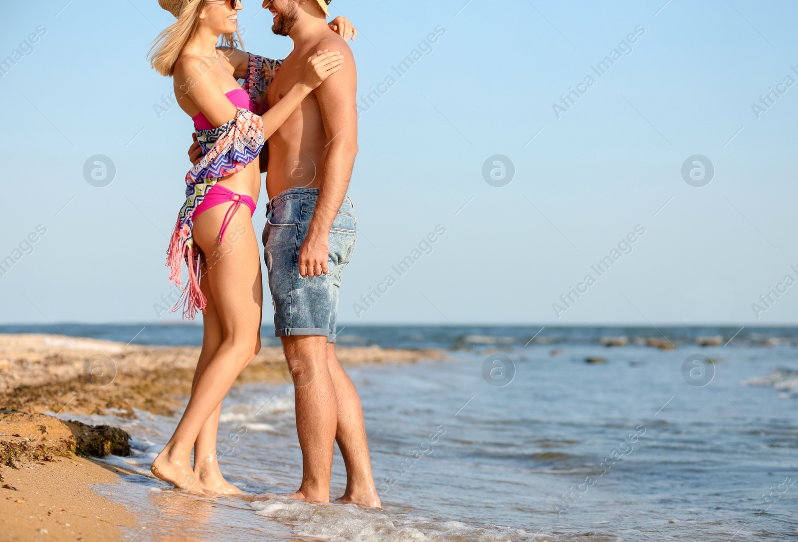 Photo of Young couple spending time together on beach, focus on legs