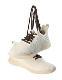 Pair of stylish shoes with laces hanging on white background