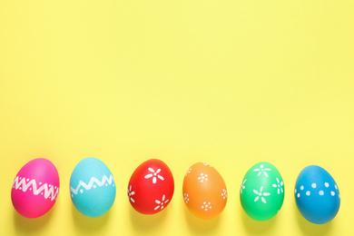 Photo of Colorful Easter eggs on yellow background, flat lay. Space for text