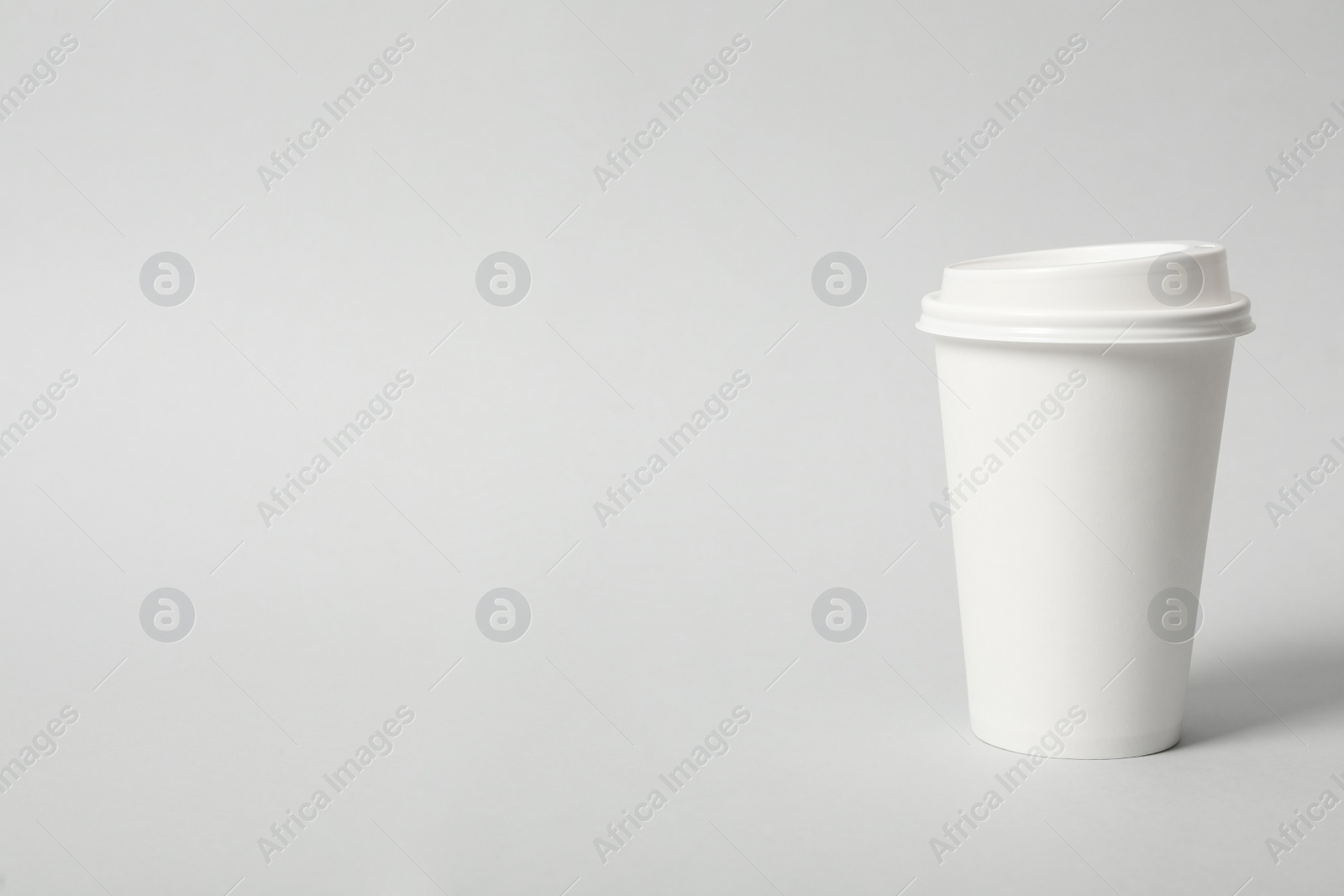 Photo of Takeaway paper coffee cup on light grey background. Space for text