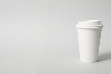 Photo of Takeaway paper coffee cup on light grey background. Space for text