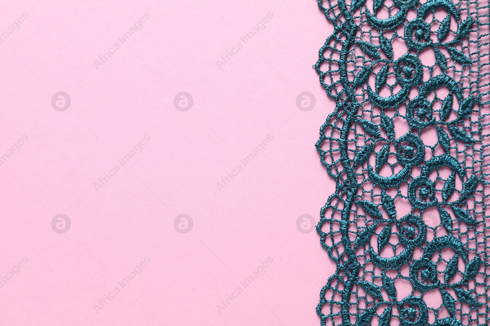 Photo of Green lace on pink background, top view. Space for text