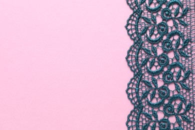 Photo of Green lace on pink background, top view. Space for text