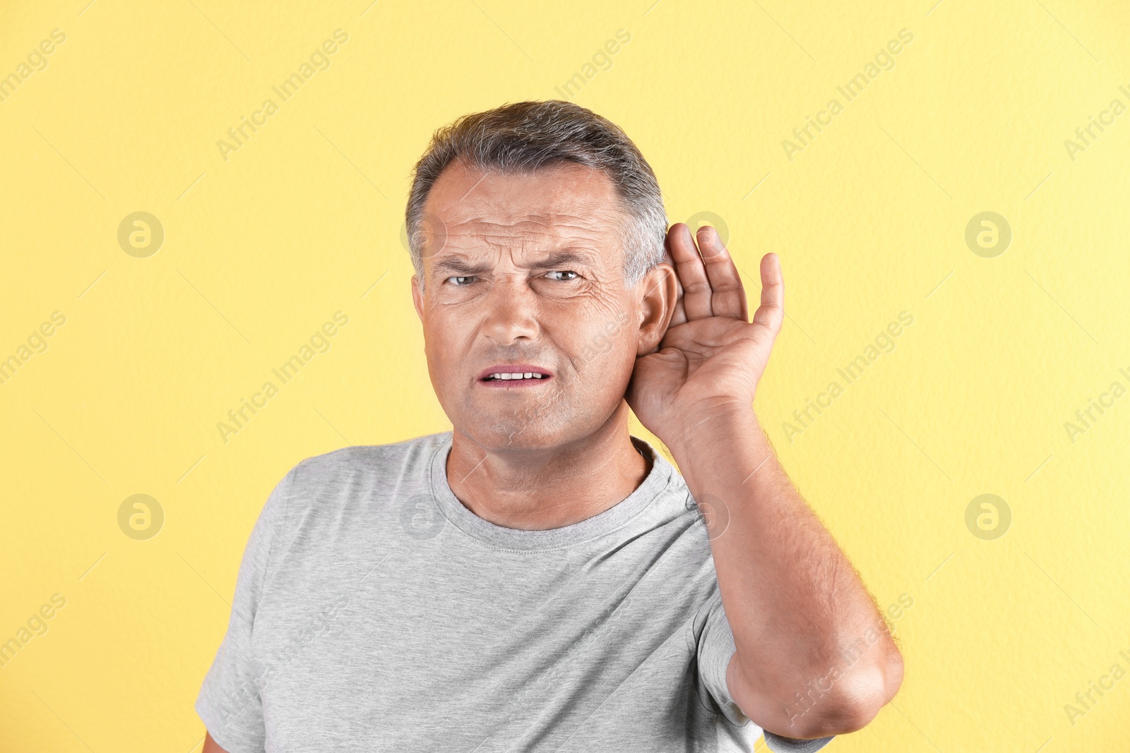 Photo of Mature man with hearing problem on color background